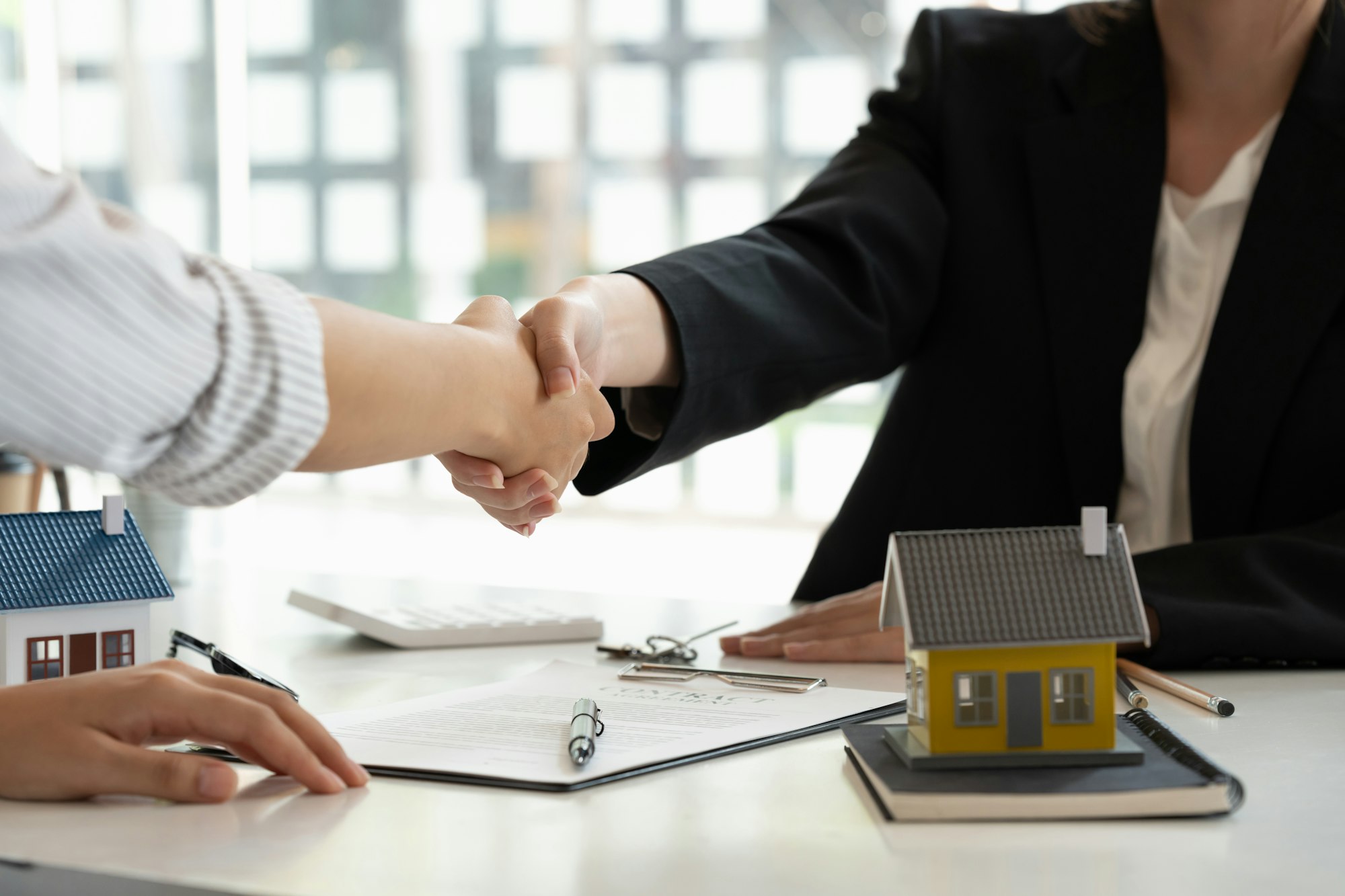 Real estate broker and customer shaking hands after signing a contract: real estate, home loan and