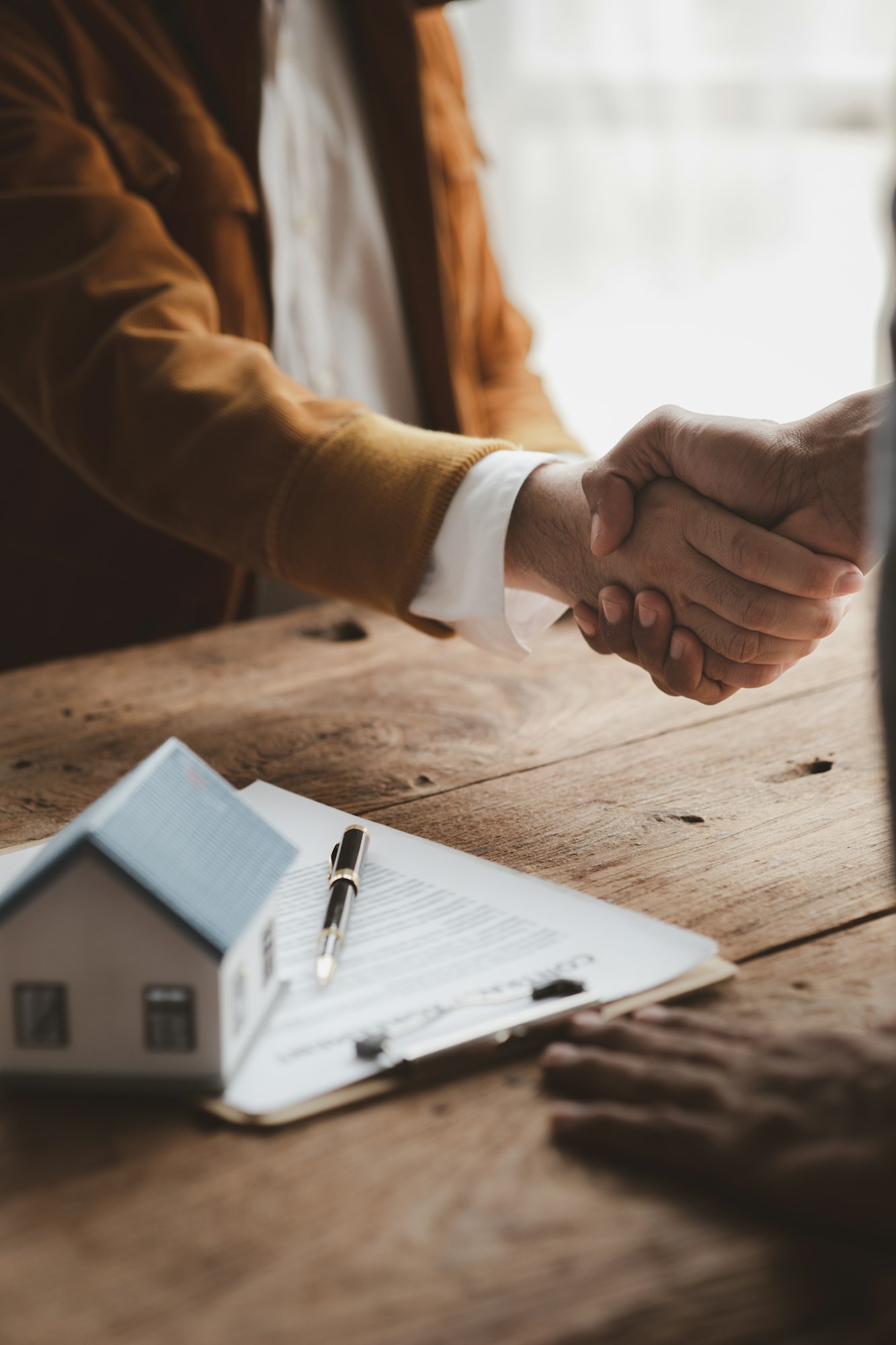 Real estate sales agents shake hands with customers of housing projects.